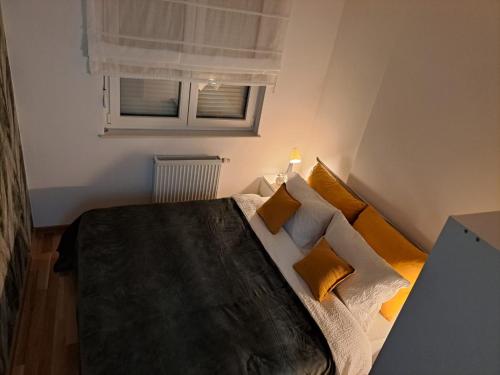 a bedroom with a bed with yellow pillows and a window at Apartmani Kosic in Banja Luka