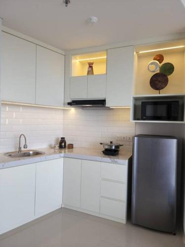 een keuken met witte kasten en een roestvrijstalen koelkast bij Batam Luxurious, Breezy 1 bedroom! in Nongsa