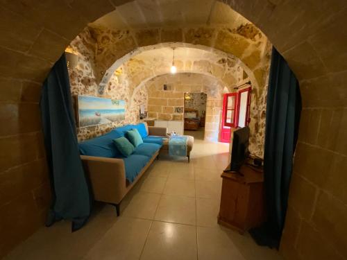 sala de estar con sofá azul en una pared de piedra en Gozo Sunset Guesthouse, en Qala