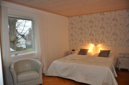 a bedroom with a bed and a chair and a window at Pensionat Ekholmen in Vessigebro