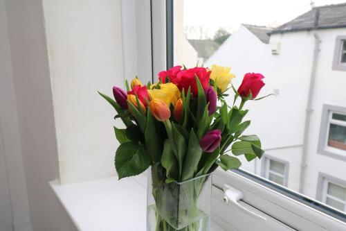 un jarrón de flores sentado en un alféizar de la ventana en Cosy Two Bedroom Cottage, en Whitehaven