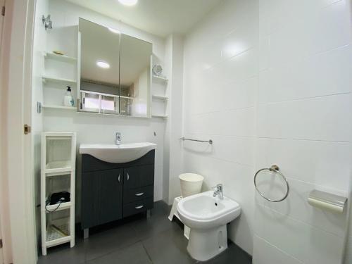 uma casa de banho branca com um lavatório e um WC em La Manga Beach Club Frontal em La Manga del Mar Menor
