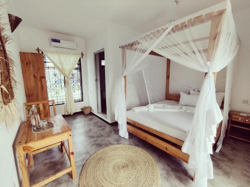 a bedroom with a canopy bed and a wooden table at Hakuna Matata Boutique in Paje