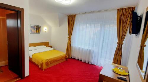 a bedroom with a yellow bed and a large window at Pensiunea Amarilis in Moieciu de Jos