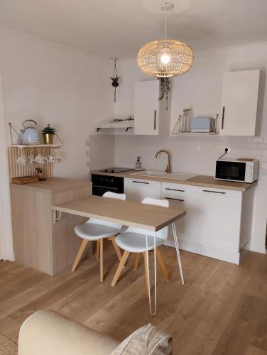 une cuisine avec une table, des chaises et un évier dans l'établissement Perle rare, appartement paisible et cosy, à Lamballe