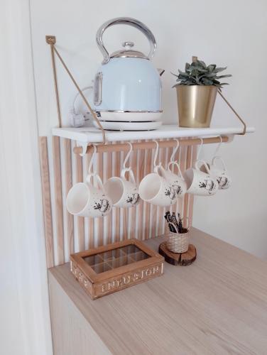 - une étagère avec des tasses à café et une théière dans l'établissement Perle rare, appartement paisible et cosy, à Lamballe