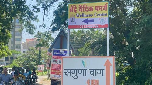 a group of signs on a street with people on bikes at Bendre's Farm Stay-Neral in Neral