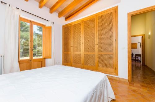 a bedroom with a white bed and a large window at YourHouse Son Jaumell in Capdepera