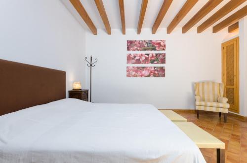 a bedroom with a white bed and a chair at YourHouse Son Jaumell in Capdepera