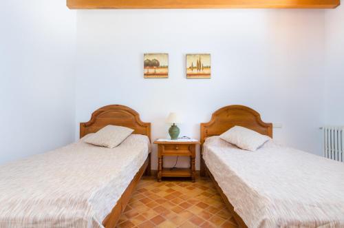 two beds in a room with a nightstand between them at YourHouse Son Jaumell in Capdepera