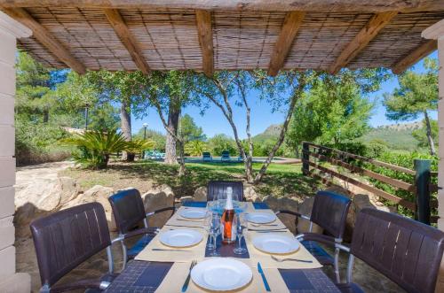 a table and chairs on a patio with a fence and trees at YourHouse Son Jaumell in Capdepera