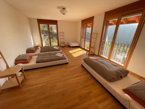 Habitación con 2 camas, suelo de madera y ventanas. en Wunderschönes Gästehaus mit grandioser Aussicht, en Gempen