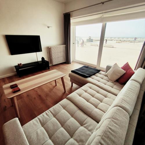 a living room with a couch and a flat screen tv at Stijlvol appartement met zeezicht Nieuwpoort in Nieuwpoort