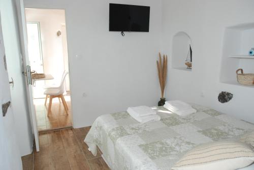 a white bedroom with a bed and a tv on the wall at Siesta Villas nearby Tzanaki Beach Livadi in Livadi Astypalaias