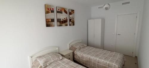 ein Schlafzimmer mit 2 Betten und einem Bild an der Wand in der Unterkunft Apartment Rose In Bloom in Benidorm