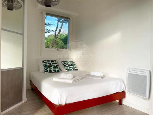 une chambre blanche avec un lit avec une fenêtre dans l'établissement Appartement Marine, à Soorts-Hossegor