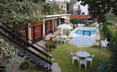 een patio met tafels en parasols naast een zwembad bij POSADA NEHUEN in Villa General Belgrano