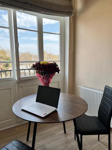 einen Laptop auf einem Tisch mit einer Blumenvase in der Unterkunft Riverfront Apartment in Tbilisi City
