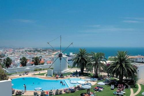 a large swimming pool with a windmill in the background at douceur d'algarve in Albufeira