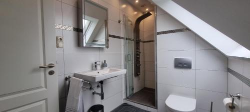 ein weißes Bad mit einem Waschbecken und einer Dusche in der Unterkunft Haus am Meer in Schweiburg