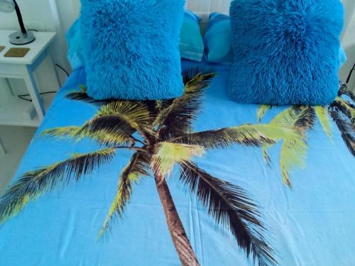 niebieskie łóżko z niebieskimi poduszkami i palmą w obiekcie Sea View Penthouse Apartment Monte Pego w mieście Pego