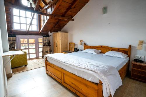 um quarto com uma grande cama de madeira com lençóis brancos em Brown Stone Villa em Bhimtal