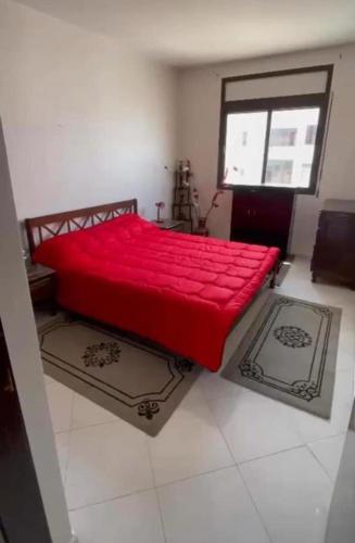 a red bed in a room with a window at Appartement in Oulad Yakoub