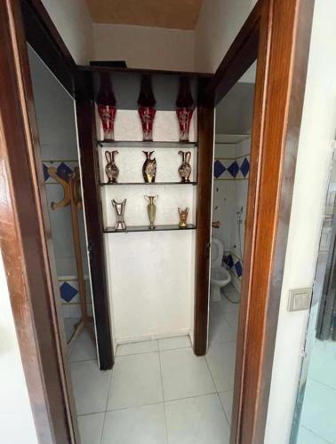 baño con aseo y puerta con estanterías en Appartement en Oulad Yakoub