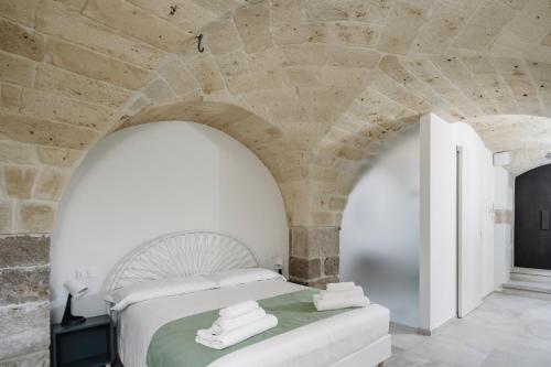 a bedroom with a white bed and a stone wall at Clementia Guest House in Altamura