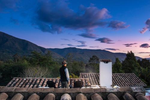 ビージャ・デ・レイバにあるPASSADHI Ayurveda & Yoga Retreatの山を見つめる屋根に立つ男