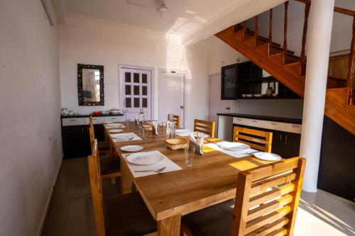 a long wooden table with chairs and a kitchen at Brown Stone Villa in Bhīm Tāl