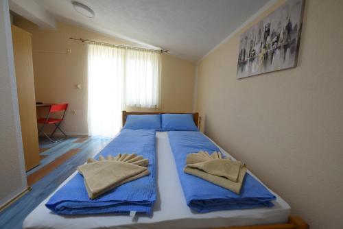 um quarto com uma cama com lençóis azuis e toalhas em LM Rooms em Banja Luka