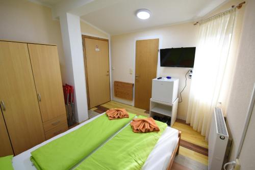 um quarto com uma cama com lençóis verdes e uma televisão em LM Rooms em Banja Luka