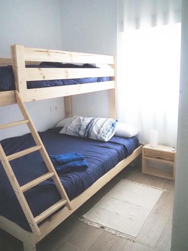 a bunk bed with a ladder next to a window at Hogar acogedor en Trujillo in Trujillo