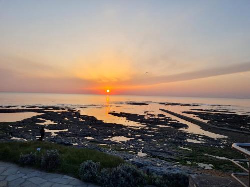 un coucher de soleil sur l'océan avec des rochers dans l'eau dans l'établissement Saint jean de monts Studio plein de charme, à Saint-Jean-de-Monts