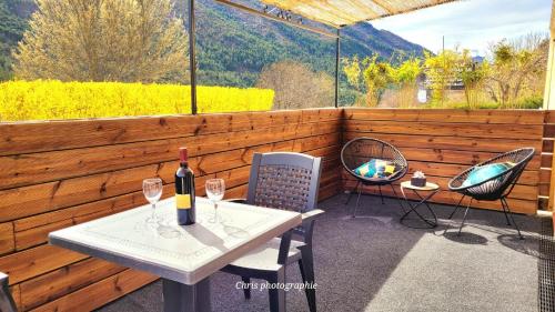 a patio with a table and two chairs and a bottle of wine at Entre Ciel et Verdon in Castellane