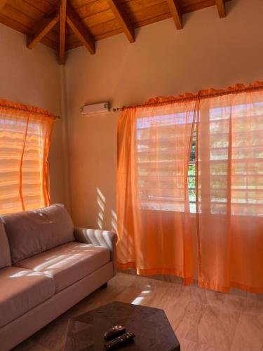 Wohnzimmer mit orangefarbenen Vorhängen und Sofa in der Unterkunft Poinciana Apartments - Holiday Rental in Woods