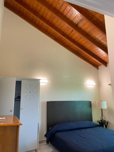 a bedroom with a blue bed and a wooden ceiling at Poinciana Apartments - Holiday Rental in Woods