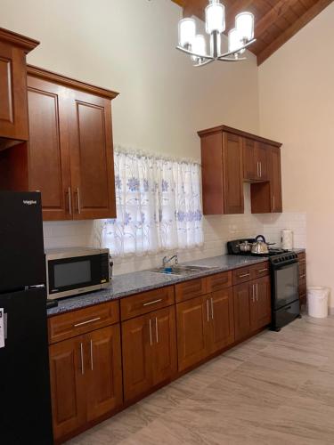 a kitchen with wooden cabinets and a black refrigerator at Poinciana Apartments - Holiday Rental in Woods