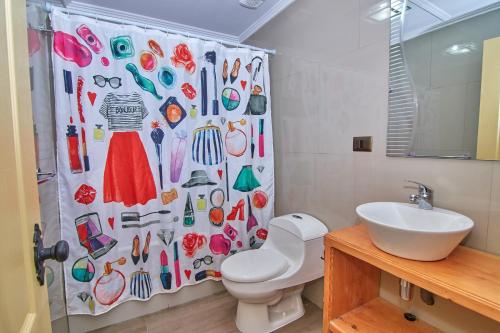 a bathroom with a shower curtain with shoes and a toilet at Mirabosque New Apartments 3 in Osorno