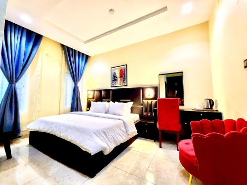 a bedroom with a bed and a desk and a red chair at Buddiez Hotel & Resort in Enugu
