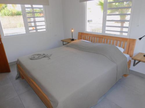 łóżko w białym pokoju z 2 oknami w obiekcie Kaya Venus Bonaire w mieście Kralendijk