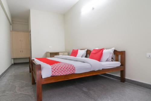 sypialnia z łóżkiem z białymi i czerwonymi poduszkami w obiekcie Appas Residency w mieście Ambalavayal