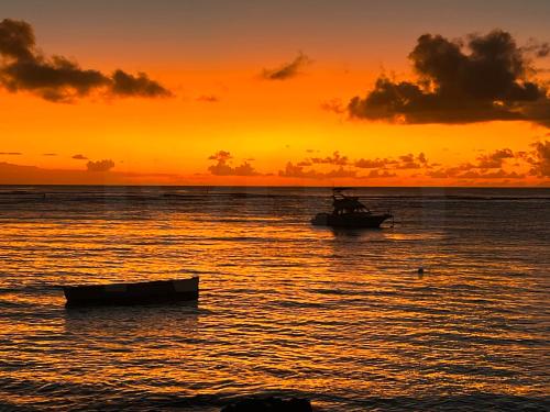 a boat in the water with a sunset at Caro's Beachfront in Trou aux Biches