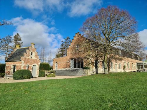 an old brick building with a tree in front of it at Eyckenmolen B&B in Lierde