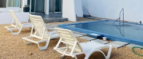 three chairs sitting next to a swimming pool at 3 bedrooms house at Trou aux Biches 10 m away from the beach with sea view furnished garden and wifi in Trou aux Biches