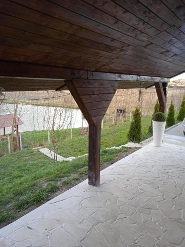 a wooden covered patio with a view of a field at Vila Sabo- Casa de vacanta cu lac de pescuit si ciubar cu hidromasaj in Sîntioana