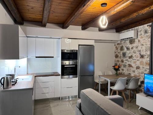 a kitchen with white cabinets and a table with a couch at Double Bee Villa with private pool in Agios Konstantinos