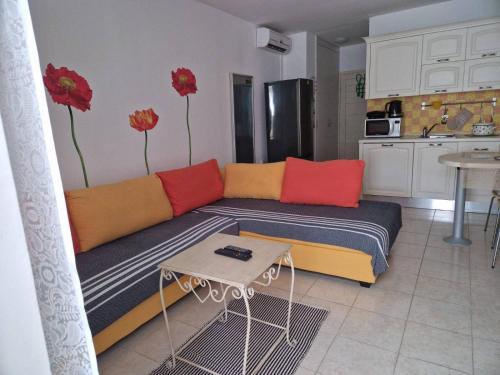 ein Wohnzimmer mit einem Sofa mit roten und orangefarbenen Kissen in der Unterkunft Studio apartman Altea in Stinica