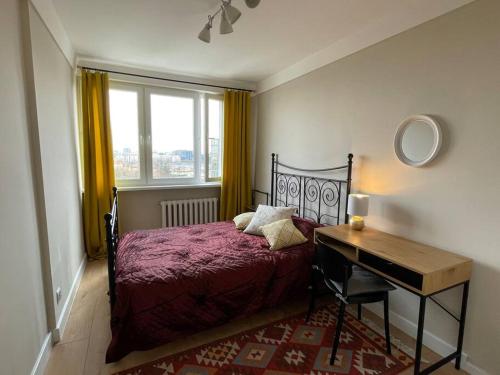 a bedroom with a bed and a desk next to a window at Apartament Pomarańczowy in Warsaw
